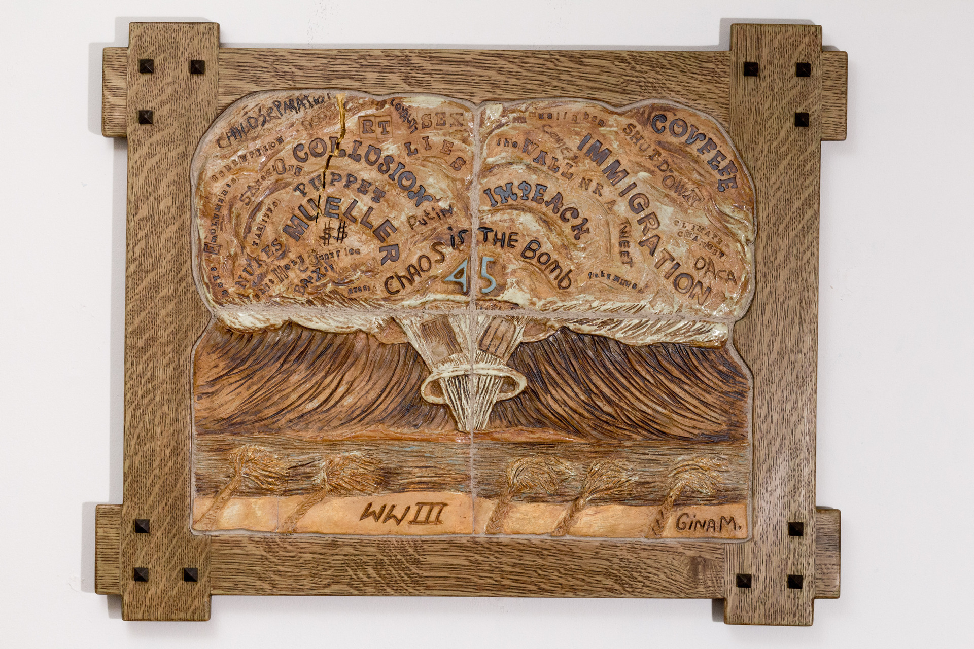 Gina M high-fired ceramic, oxide wash wood, stain hanging sculpture of an atomic bomb that depicts the destructive nature of disinformation and the weaponization of words.