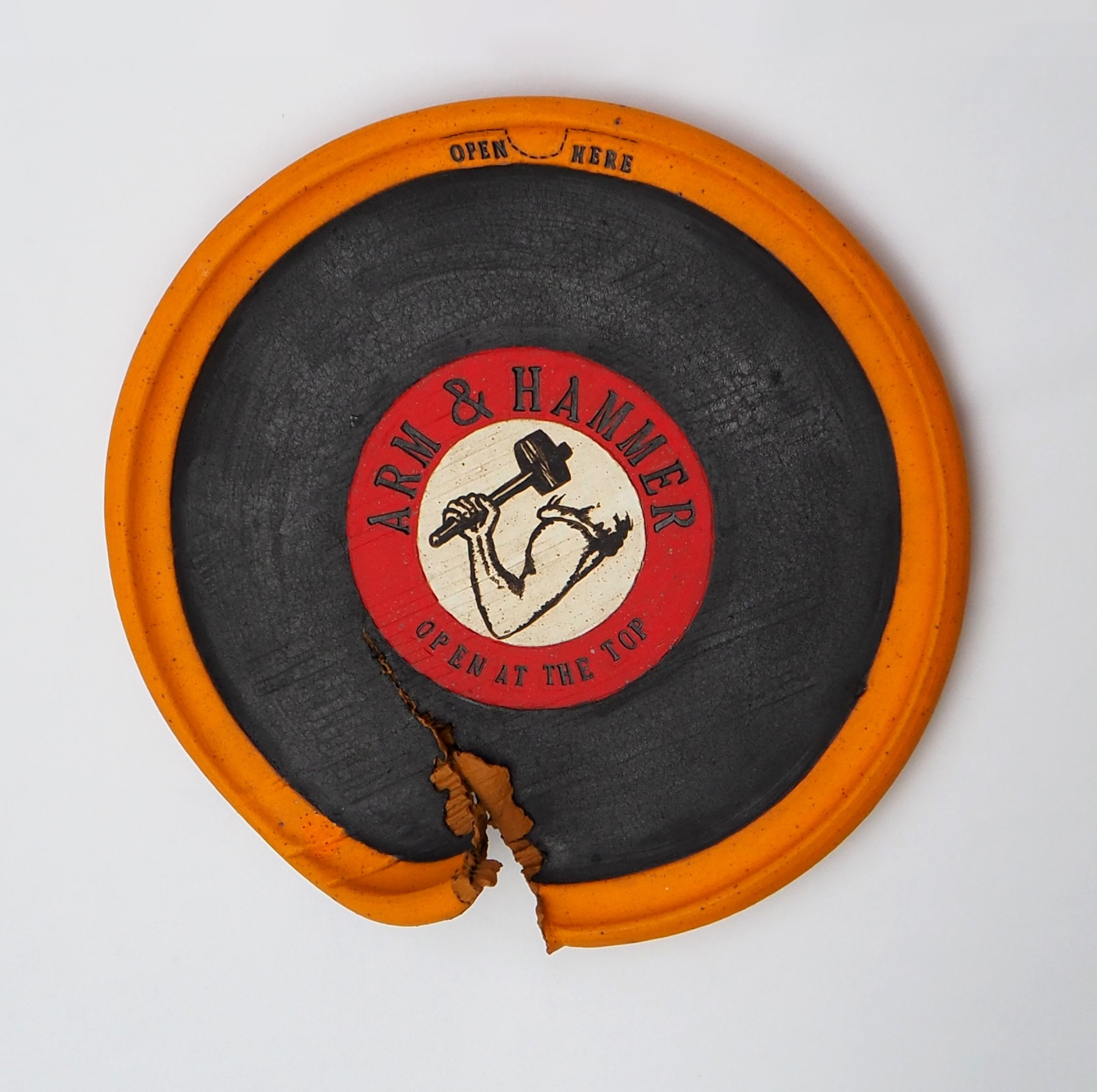 Connie Major hanging circular sculpture depicts a package torn at the bottom of the circle. The label 